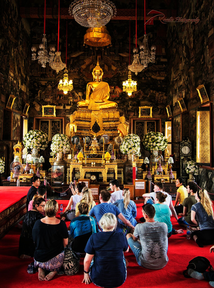 Elaborate golden interior of a temple with tourists