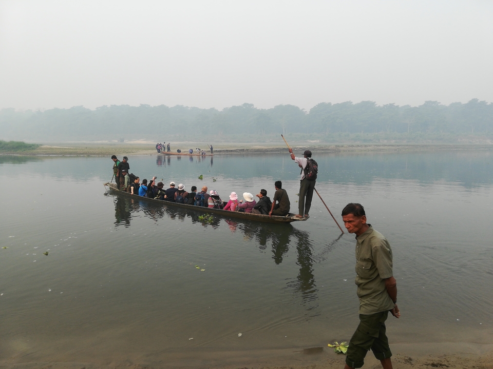 Personnes sur un long bateau en bois sur une rivière.