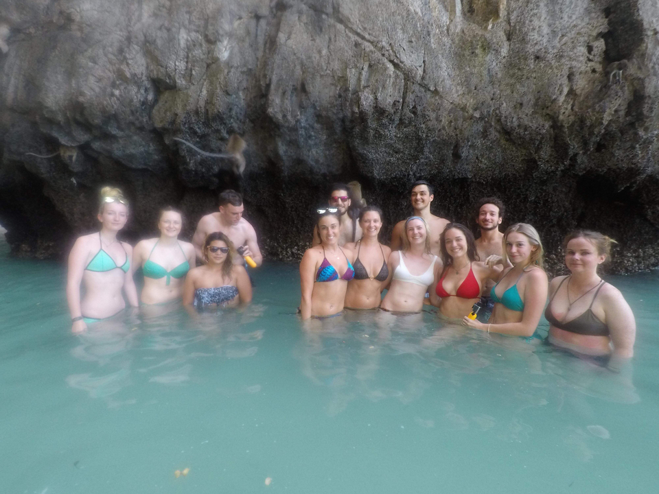 Group of people in water near cliffs.