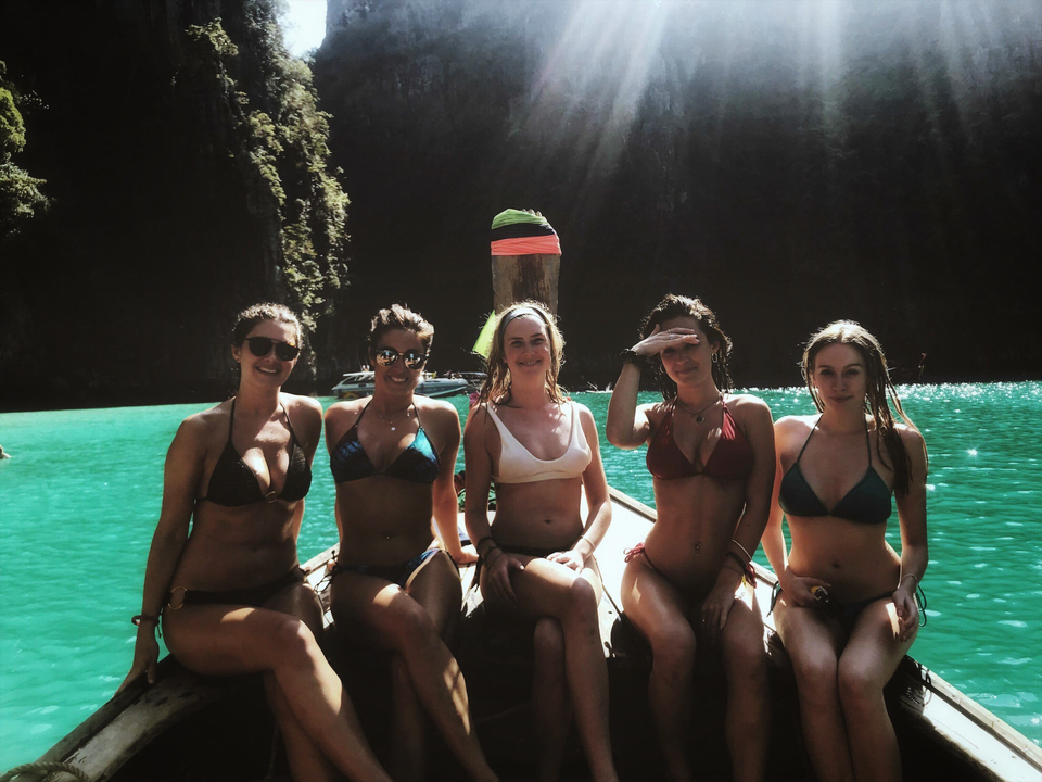 Five women sitting on a boat in a lagoon.