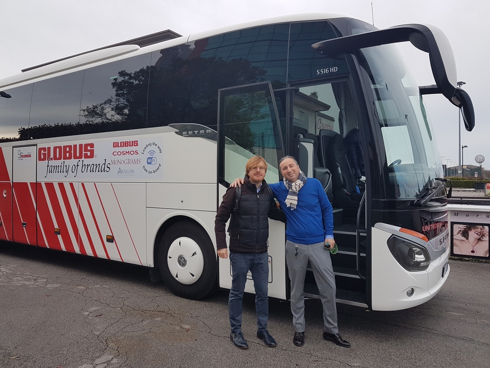 Deux hommes posant à côté d'un bus de tourisme.