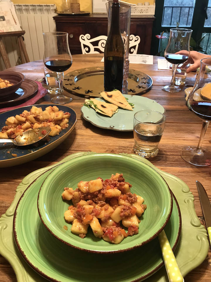 Table avec des assiettes de gnocchi et de pain avec des verres à vin.