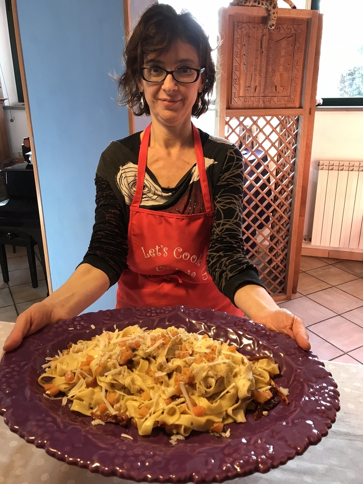 Femme tenant un plat de pâtes maison.