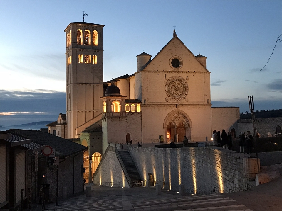 Basilique d'Assise au crépuscule avec façade illuminée.