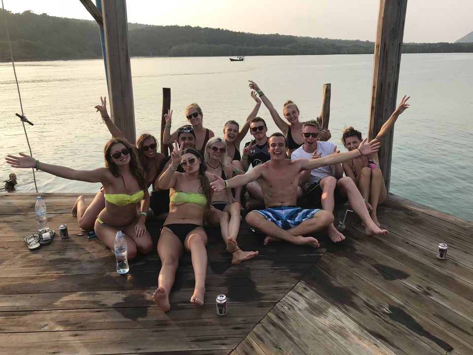 Group of friends posing on a wooden deck by the water.