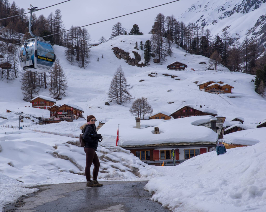 Personne debout dans un village de montagne enneigé avec un téléphérique.