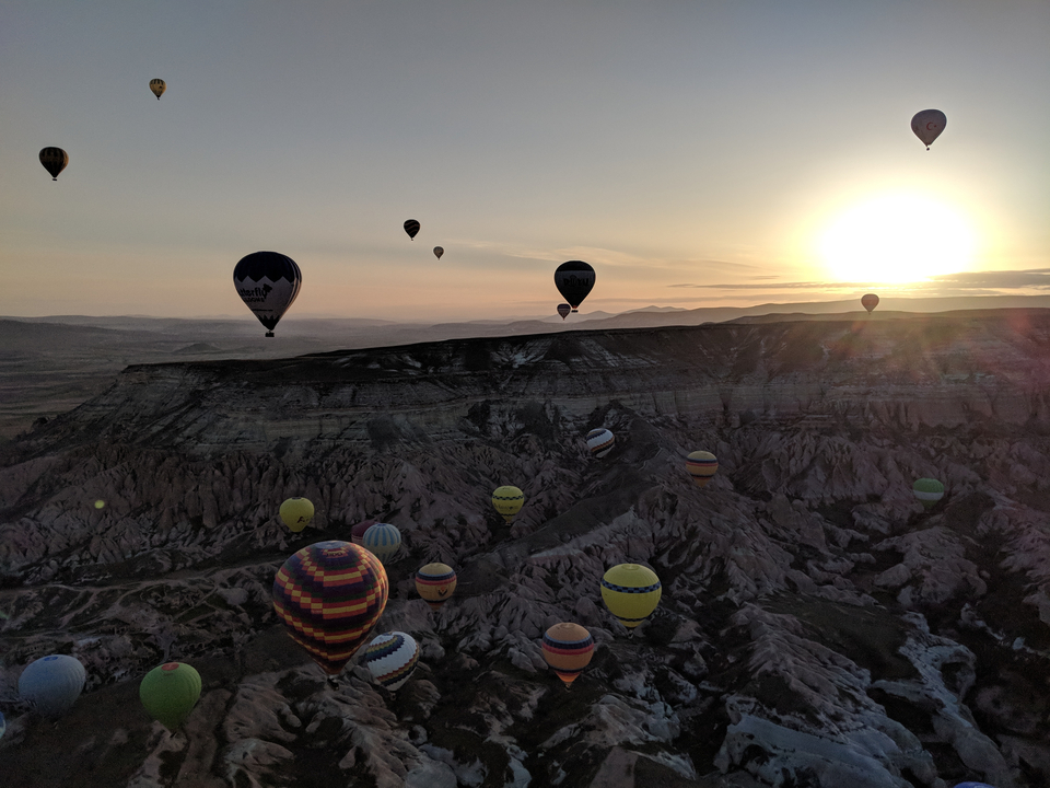 Montgolfières survolant un paysage rocheux au lever du soleil.