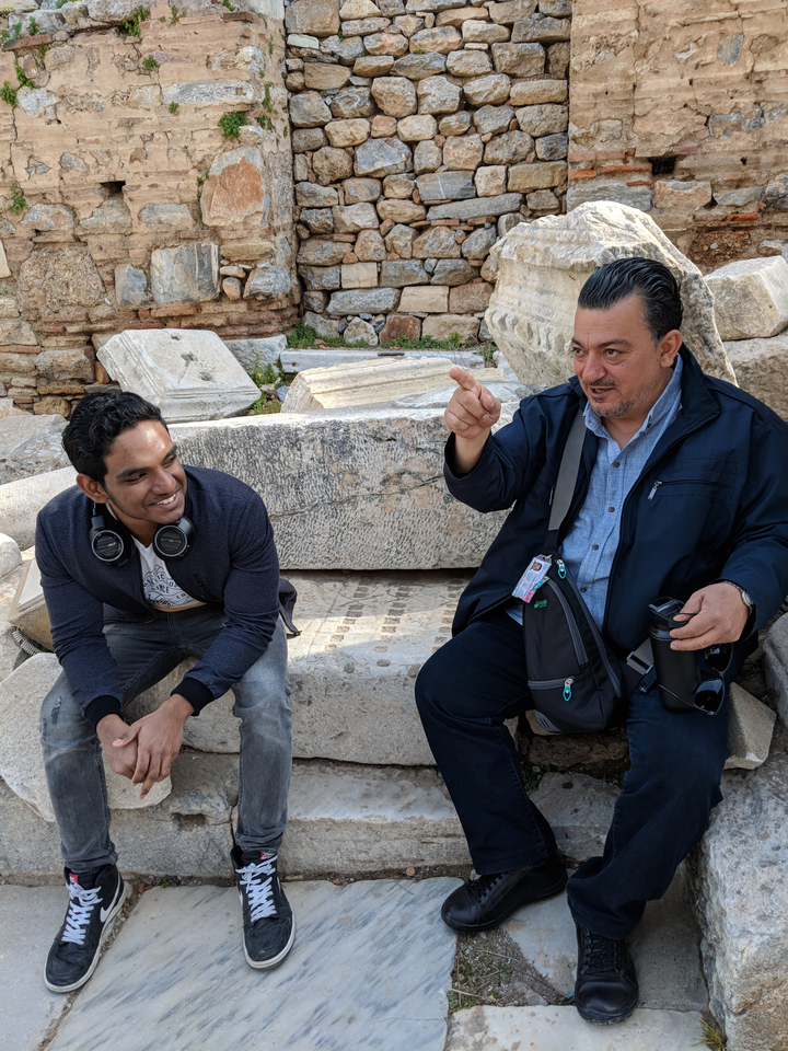 Deux personnes interagissent dans un décor de ruines anciennes.