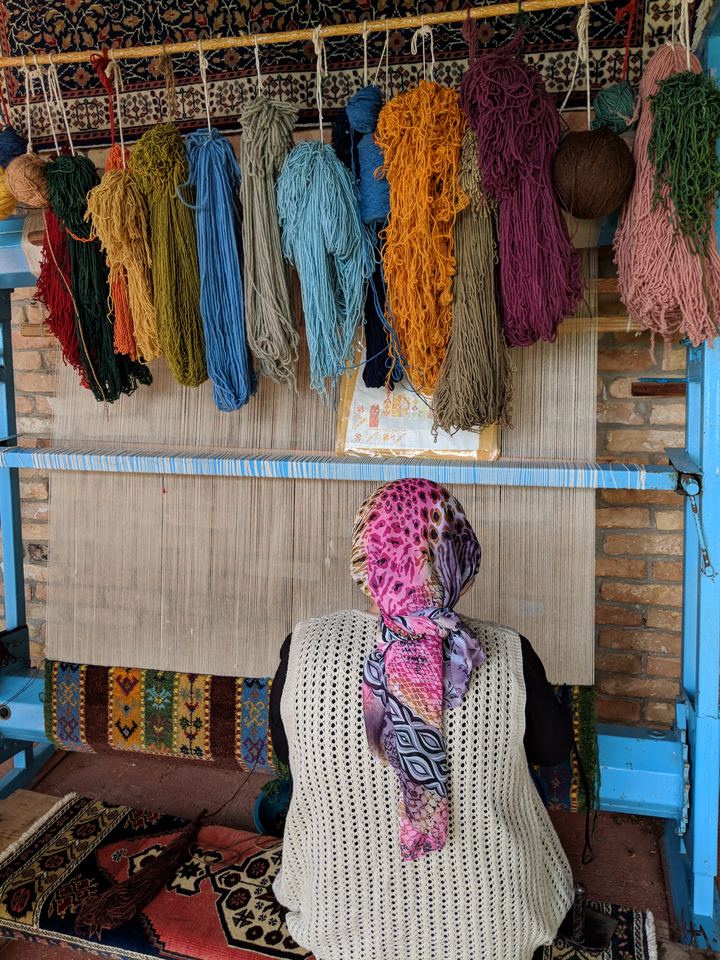 Personne tissant sur un métier à tisser avec des fils colorés.