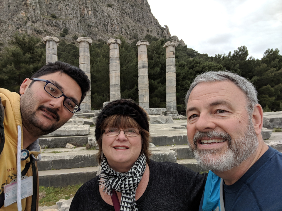 Trois personnes posant avec des colonnes anciennes.