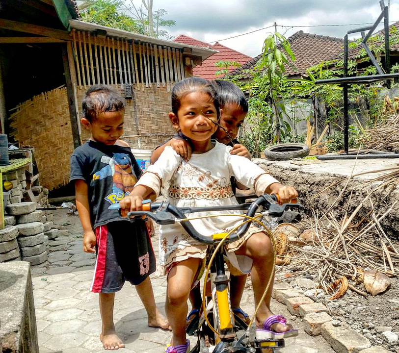 Children playing joyfully with a bicycle.
