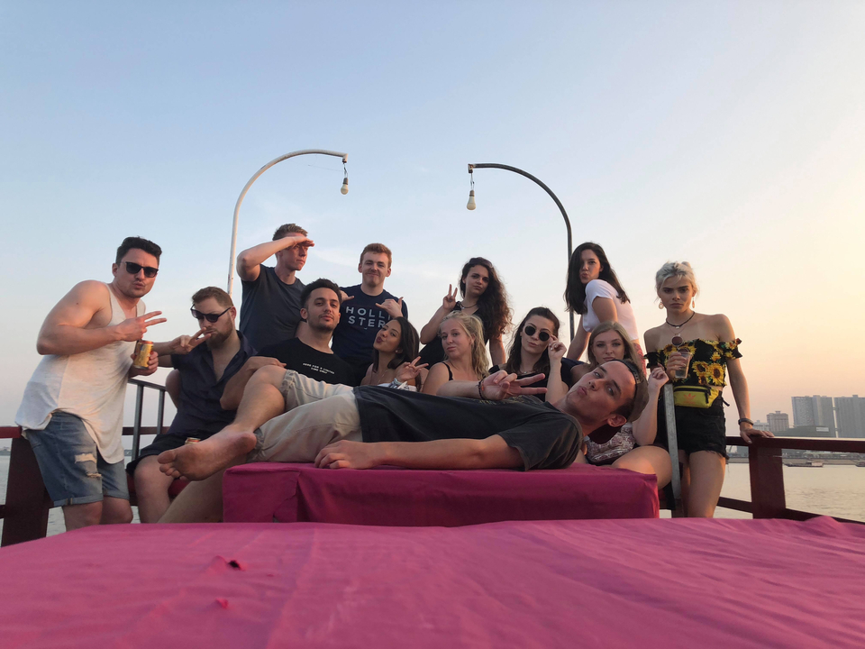 Groupe de personnes posant sur un bateau au coucher du soleil.