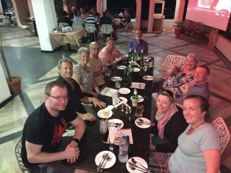 Groupe de personnes assises à une table de dîner à l'intérieur.