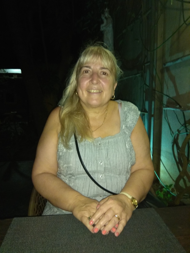 Femme assise et souriante à l'intérieur en basse lumière.