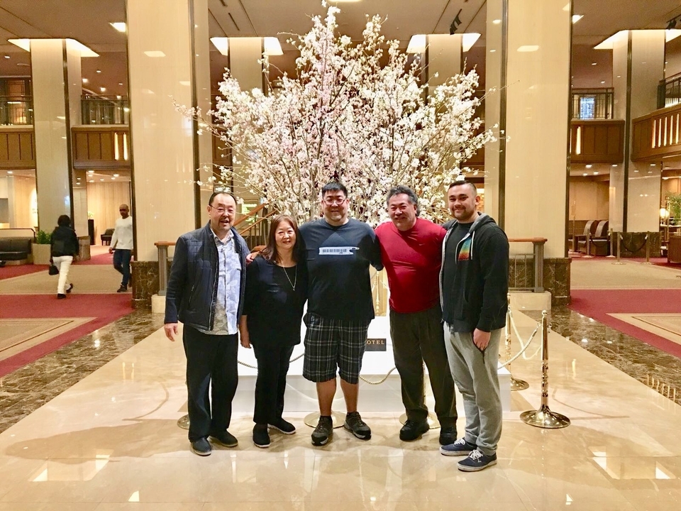 Groupe de personnes posant dans le hall d'un hôtel décoré de fleurs de cerisier.