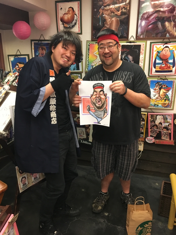 Deux personnes tenant un portrait caricatural et souriant.