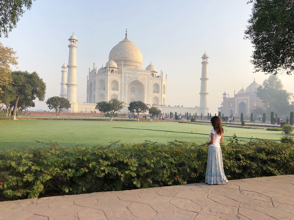 Une femme observe le Taj Mahal depuis un jardin.