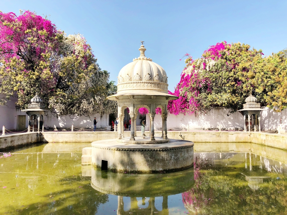 Un pavillon décoré entouré de fleurs de bougainvilliers colorées et d'un bassin réfléchissant.