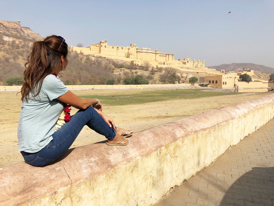 Une femme est assise sur un mur surplombant un fort historique.