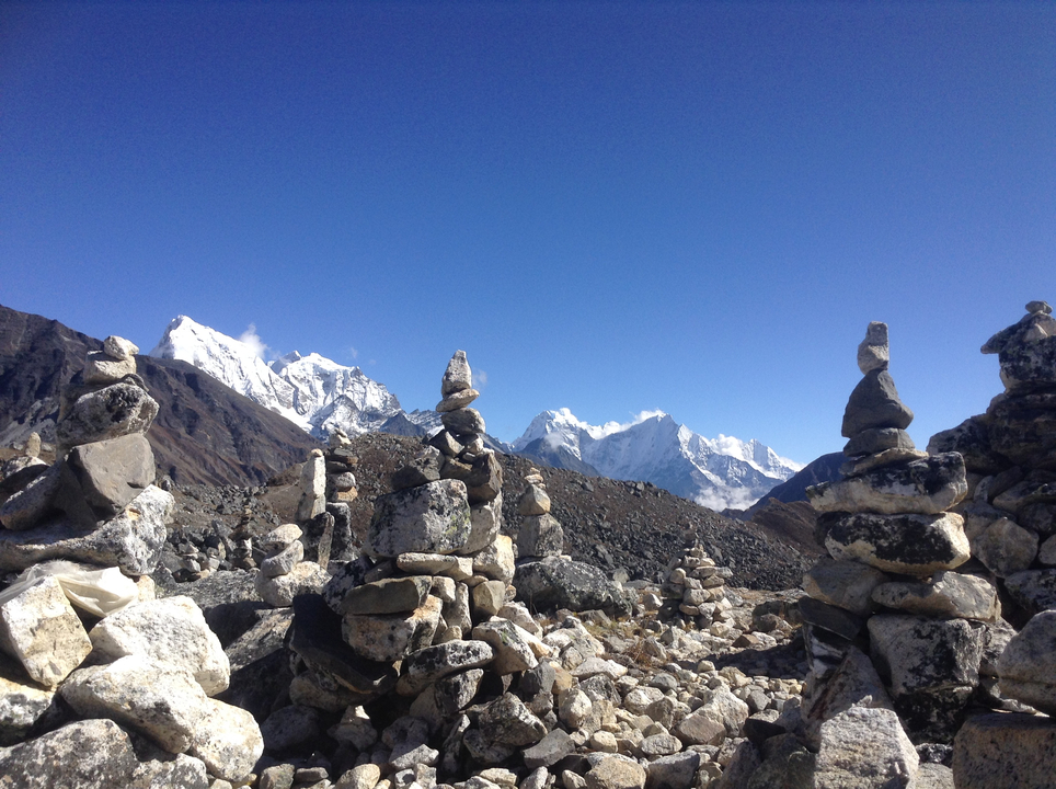 Cairns dans un paysage montagneux avec des sommets enneigés en arrière-plan.