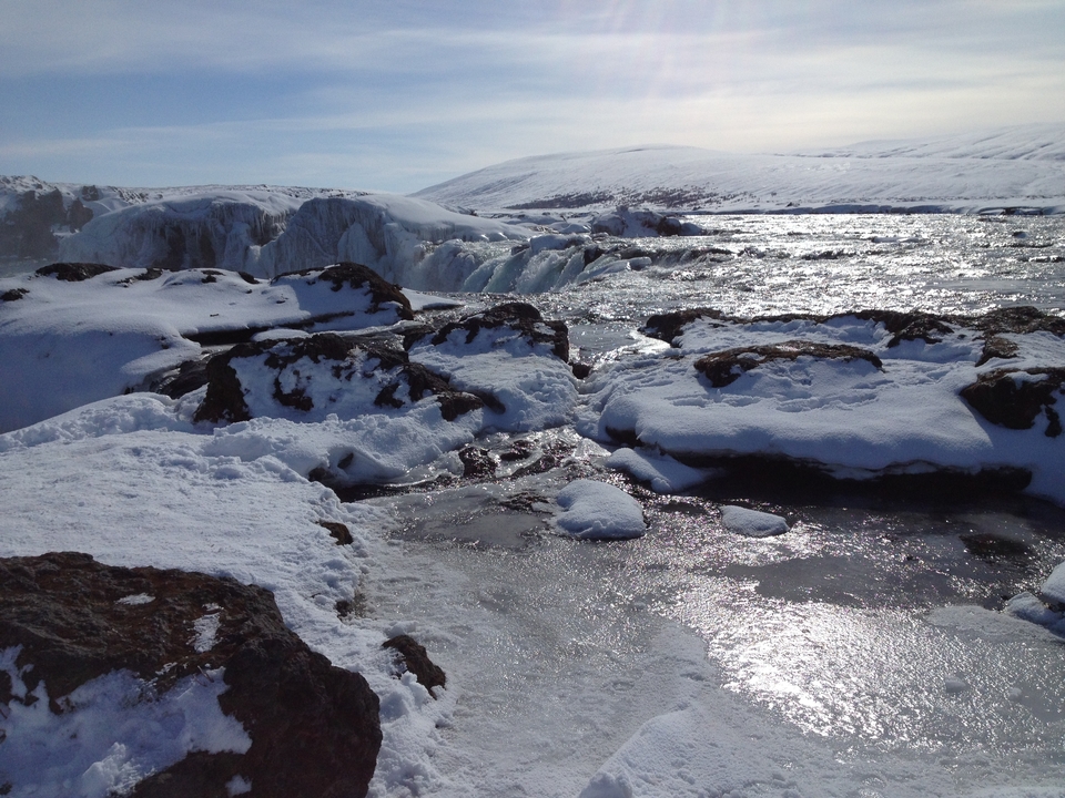 Rivière glacée s'écoulant à travers des rochers enneigés.