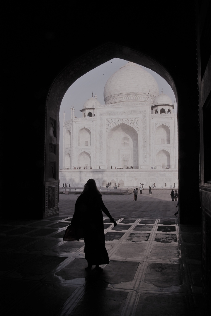 Besucher betrachten das Taj Mahal von einem Torbogen aus.
