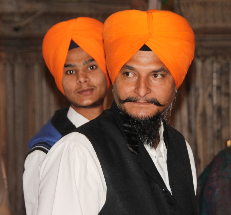 Zwei Männer in traditioneller Kleidung mit orangefarbenen Turbanen.