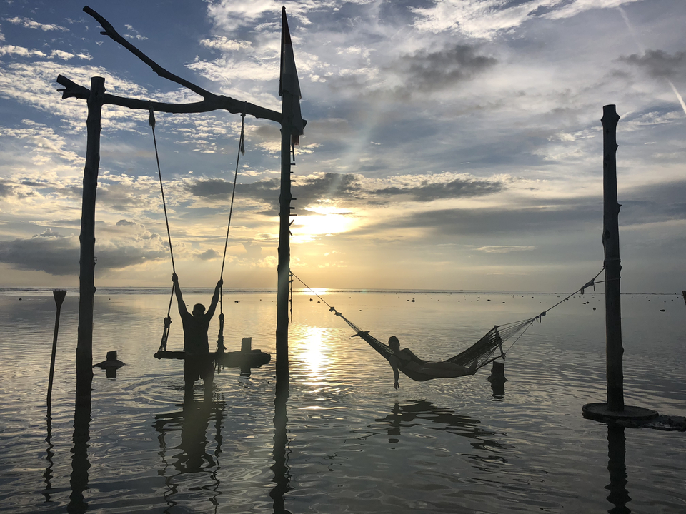 Silhouettes in a hammock during sunset at the beach