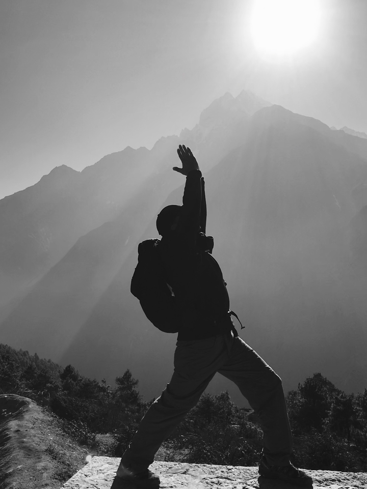Silhouette d'une personne s'étirant sur un fond de montagnes.