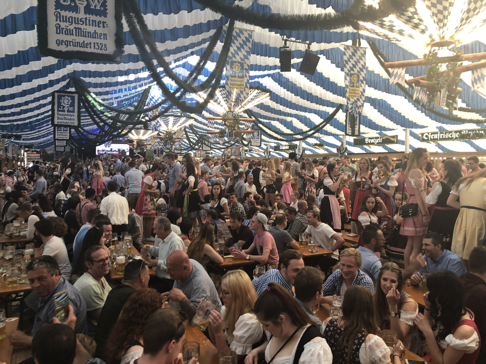 Grande foule dans une tente à bière décorée, probablement pour l'Oktoberfest.