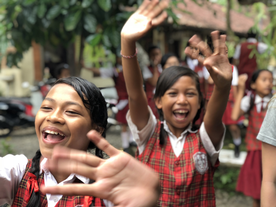 Des enfants en uniforme d'écolier saluent avec enthousiasme.