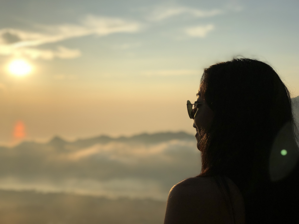Une personne se détachant sur un coucher de soleil avec des nuages en contrebas.