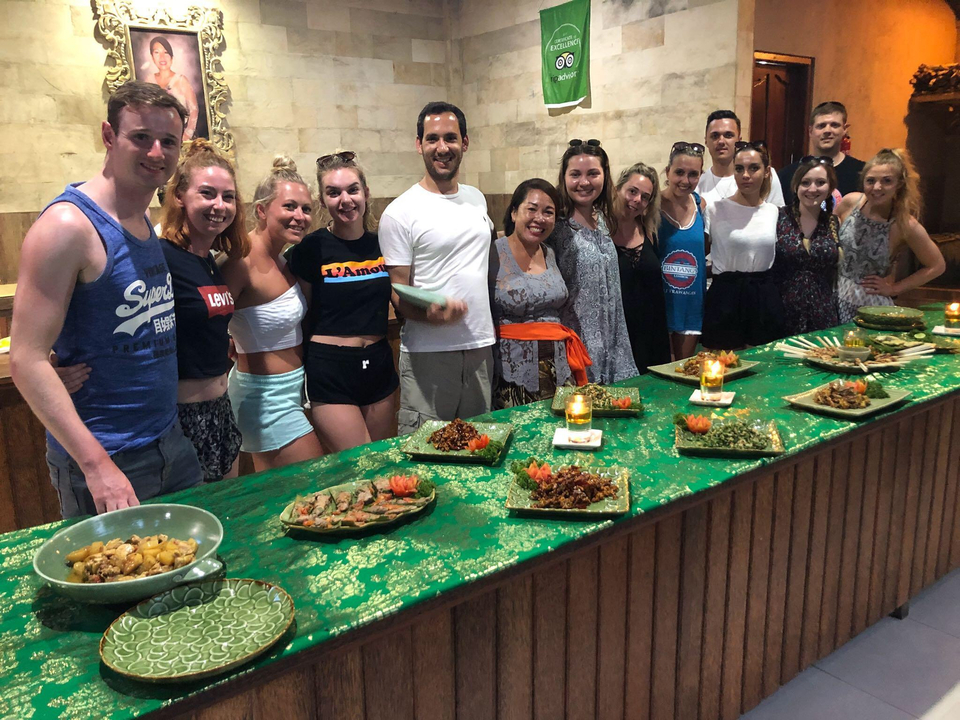 Un groupe de personnes debout derrière une table où sont disposés des plats variés.