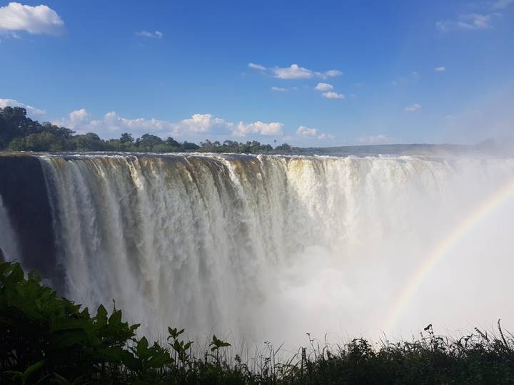 Victoria Falls in full flow with a rainbow in the mist.