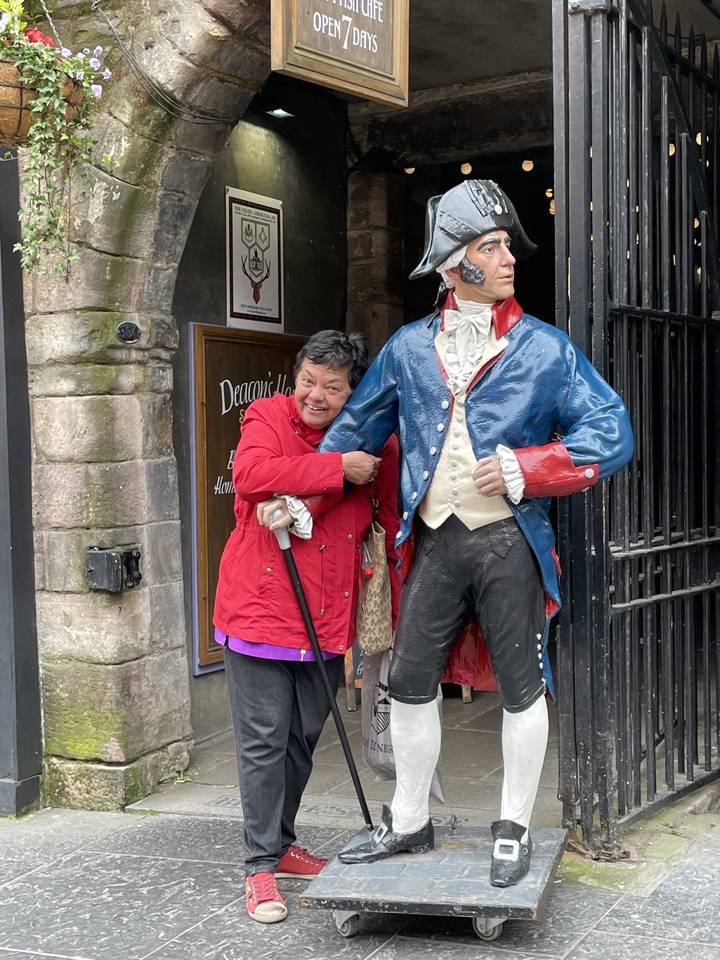 Femme posant avec une statue de pirate dans une rue de la ville.