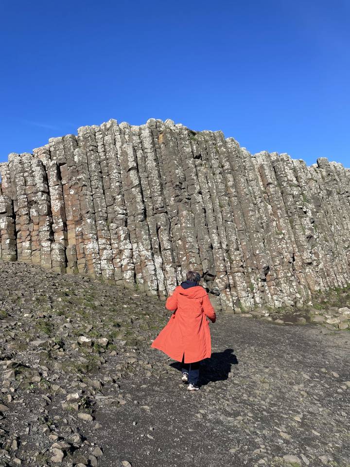 Personne en manteau lumineux regardant des colonnes de basalte.