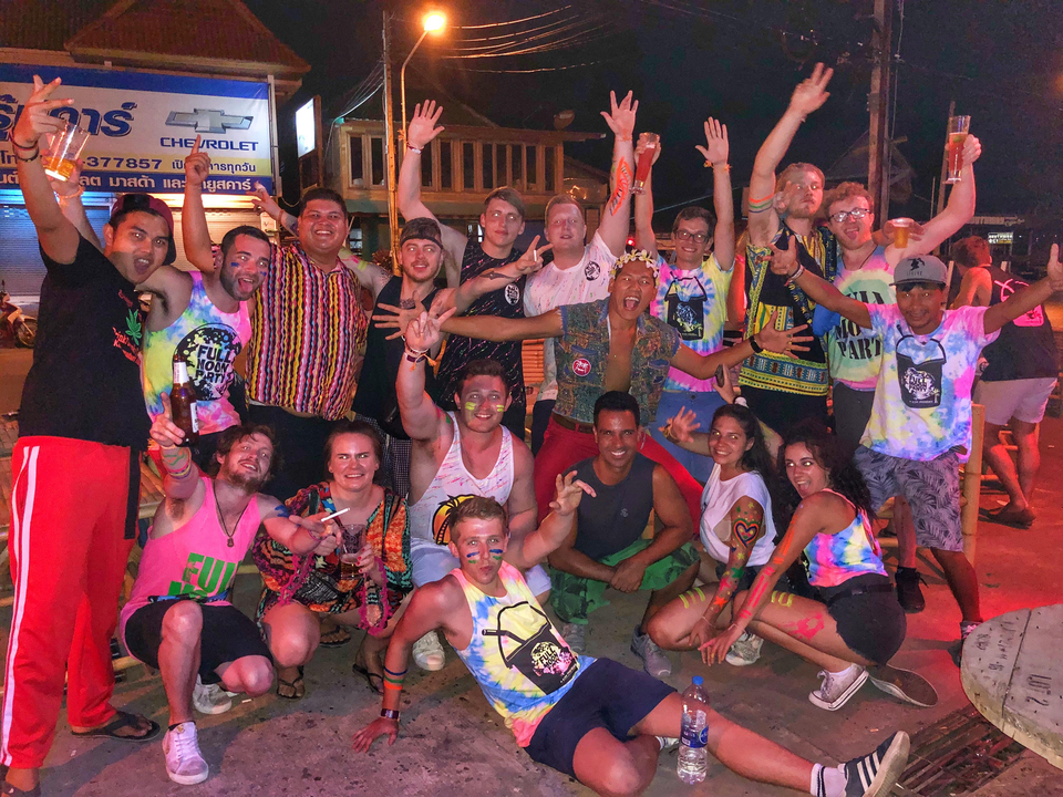A large group of people posing together, some with painted faces and colorful shirts.
