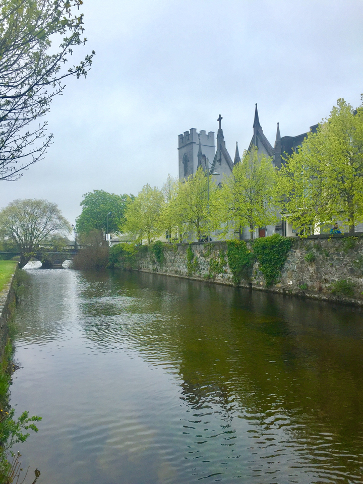 Église au bord d'une rivière bordée d'arbres.
