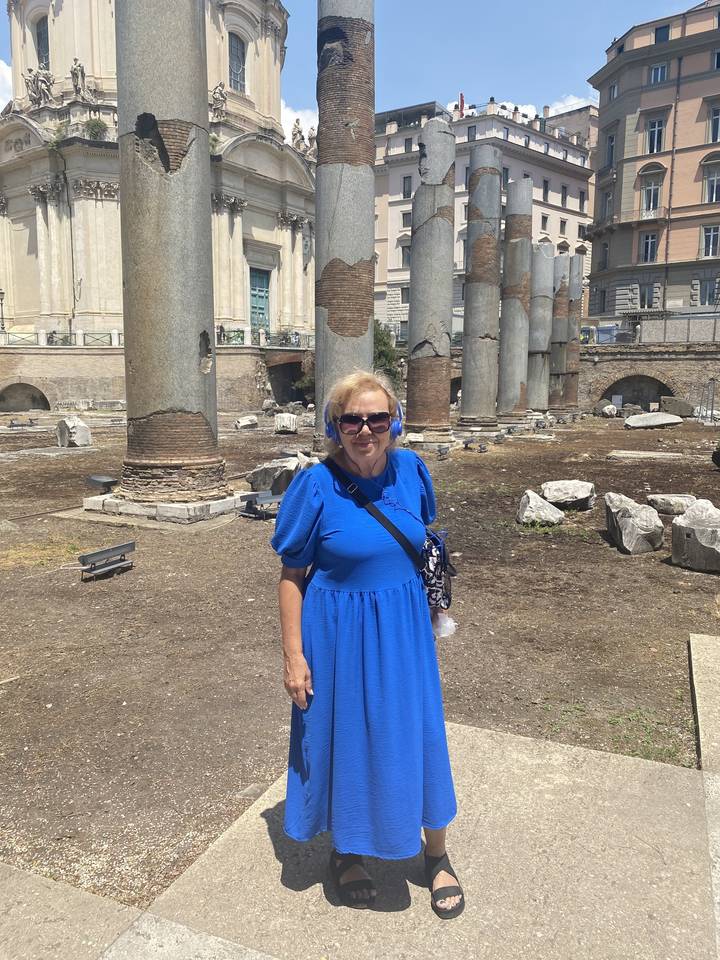 Person posing among historic ruins with pillars.