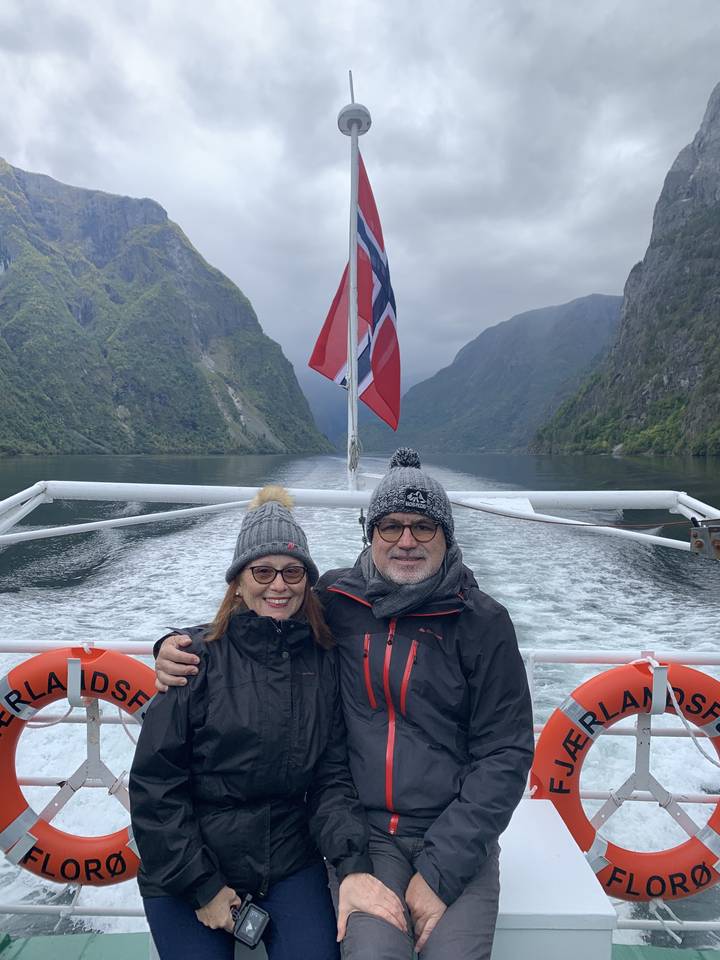Couple sur un bateau avec un drapeau norvégien et des montagnes.