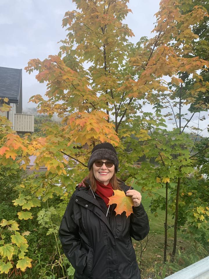 Femme tenant une feuille colorée dans un parc.