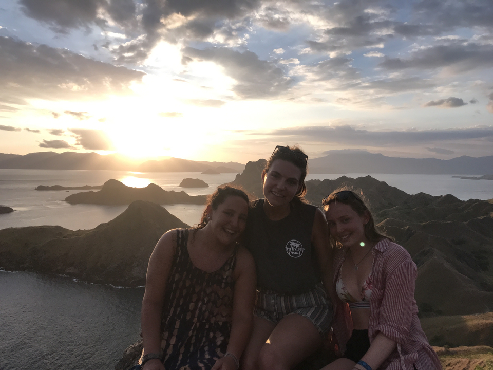 Group smiling with scenic mountains during sunset.