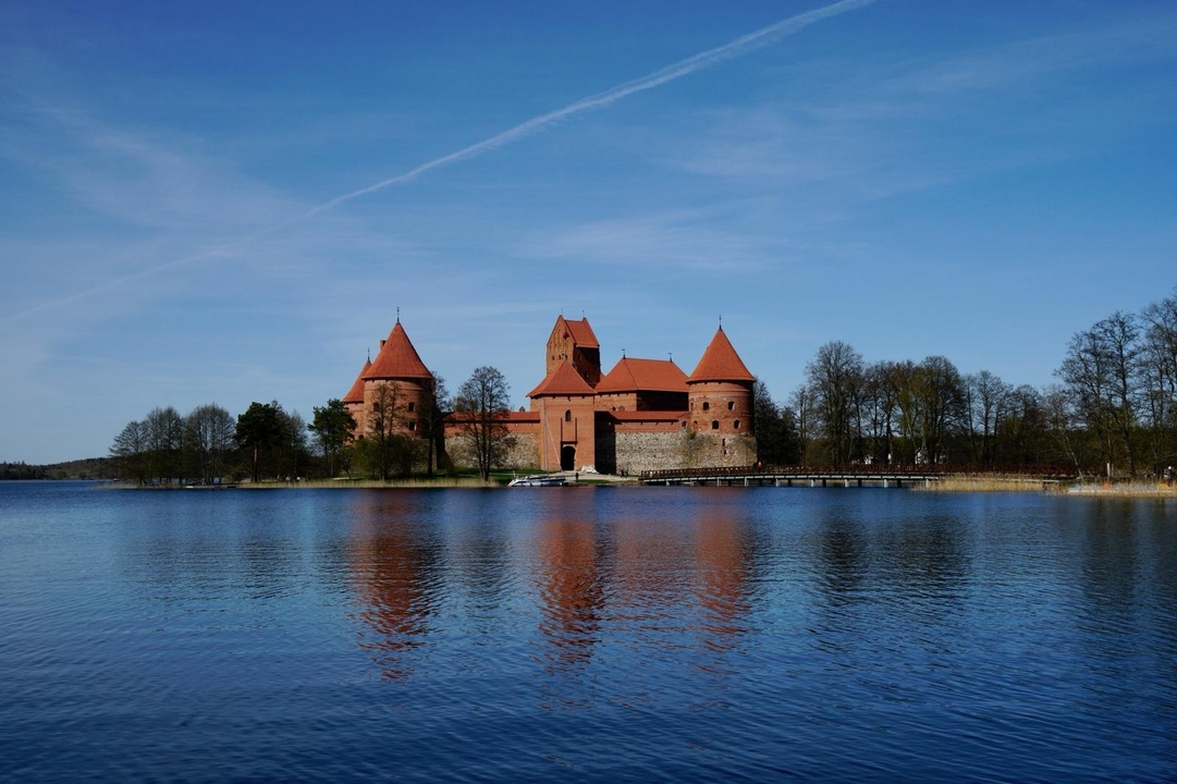 Un château médiéval sur une île entourée d'eau sous un ciel bleu.
