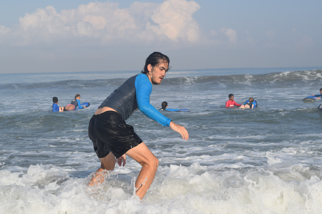 Person surfing the waves with others in the background.