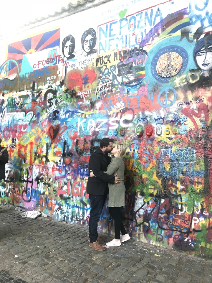 Couple s'embrassant devant un mur de graffitis colorés.