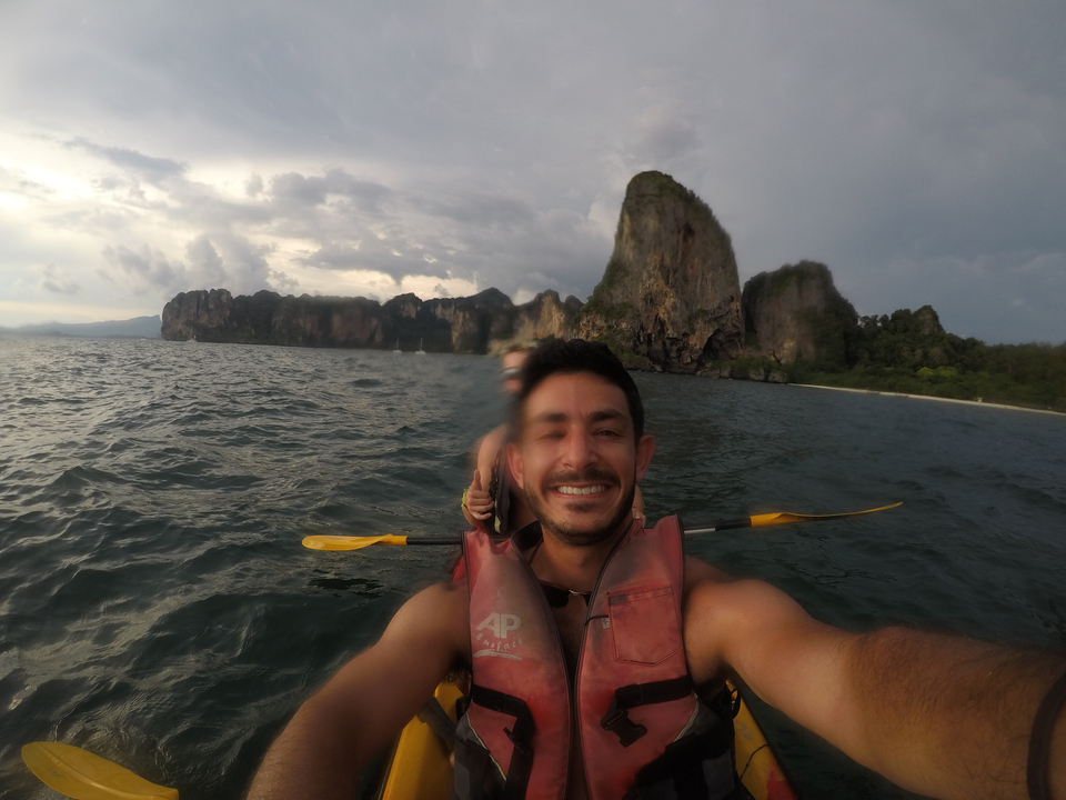 Person kayaking on the sea near rugged cliffs.