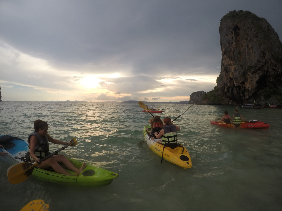 Groups of people kayaking near dramatic rock formations.
