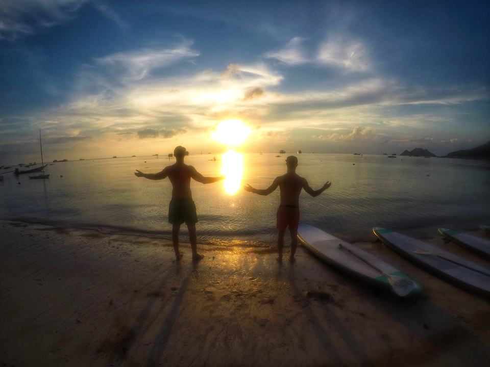 Two people enjoying a beach sunset with surfboards.