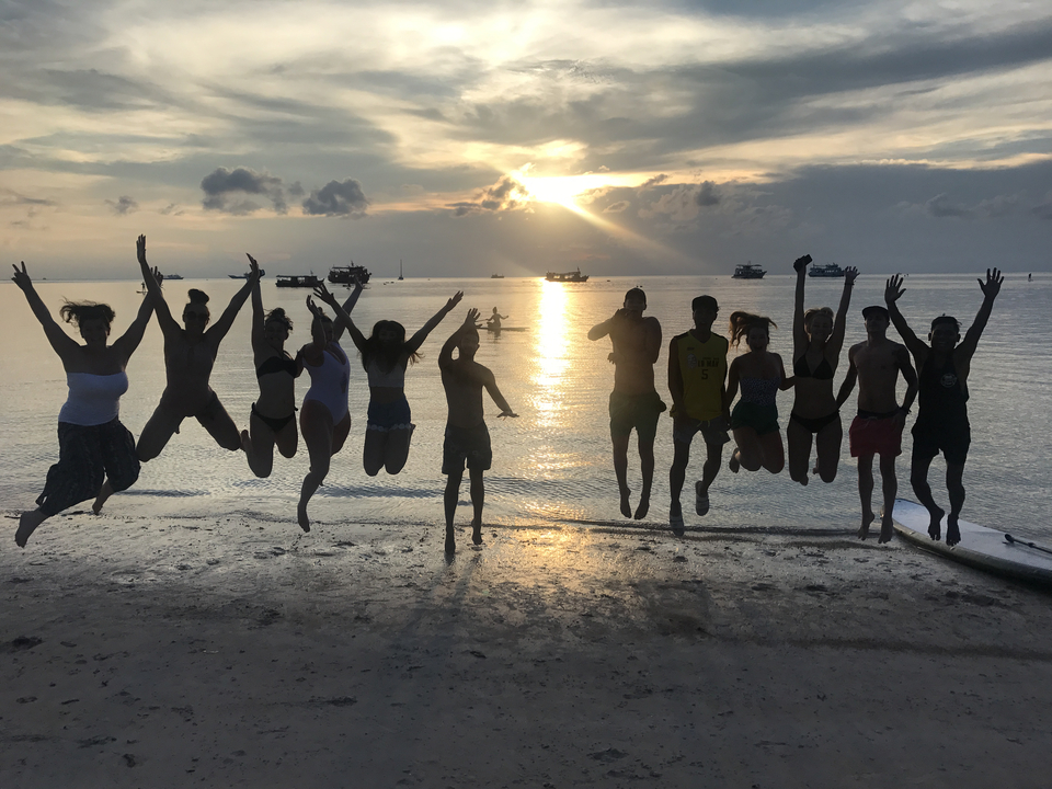 Group jump shot at sunset on the beach.