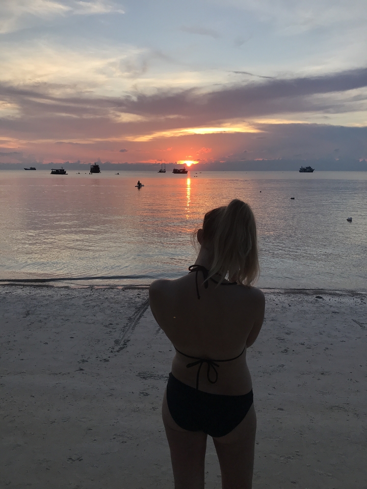 Silhouette of a person watching the sunset on a beach.